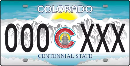 License plate of white snowy mountains and sun setting behind them. In the center is the Colorado logo with the state capitol building in the center.