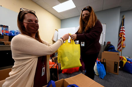 Training Specialist Shannon Streif and Administrative Assistant Jessica Reese, both Division of Motor Vehicles Team Members, show one of the donation bags as the fill empty boxes with the bags on Monday, Dec. 6 at Colorado Department of Revenue (DOR) headquarters in Lakewood. DOR Team Members donated almost 9,000 winter items to Volunteers of America, Veterans Program  for homeless and at-risk U.S. military veterans. (Derek Kuhn/Colorado DOR Photo) 