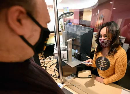 Photo of a DMV employee demonstrating how to use a PocketTalk translator. 