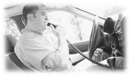 Man sitting in drivers seat of car breathing into an ignition breathilyzer device before the car will start