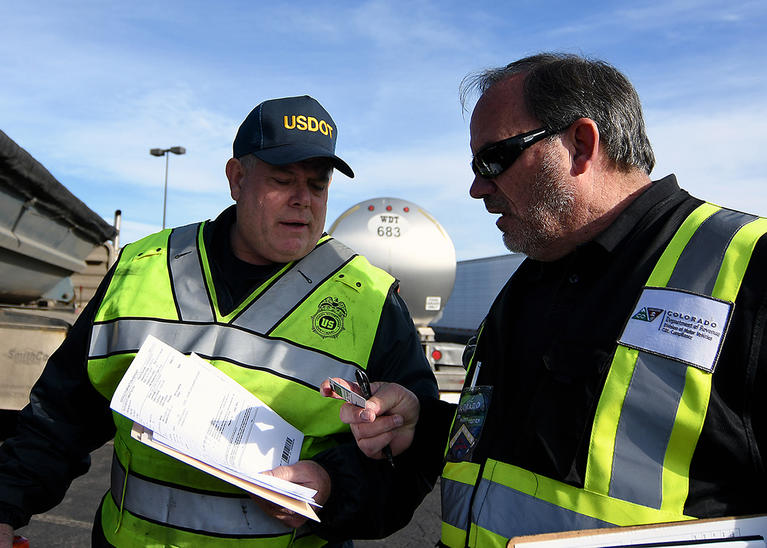 A DMV Team Member works a USDOT partner as they both wear safety vests